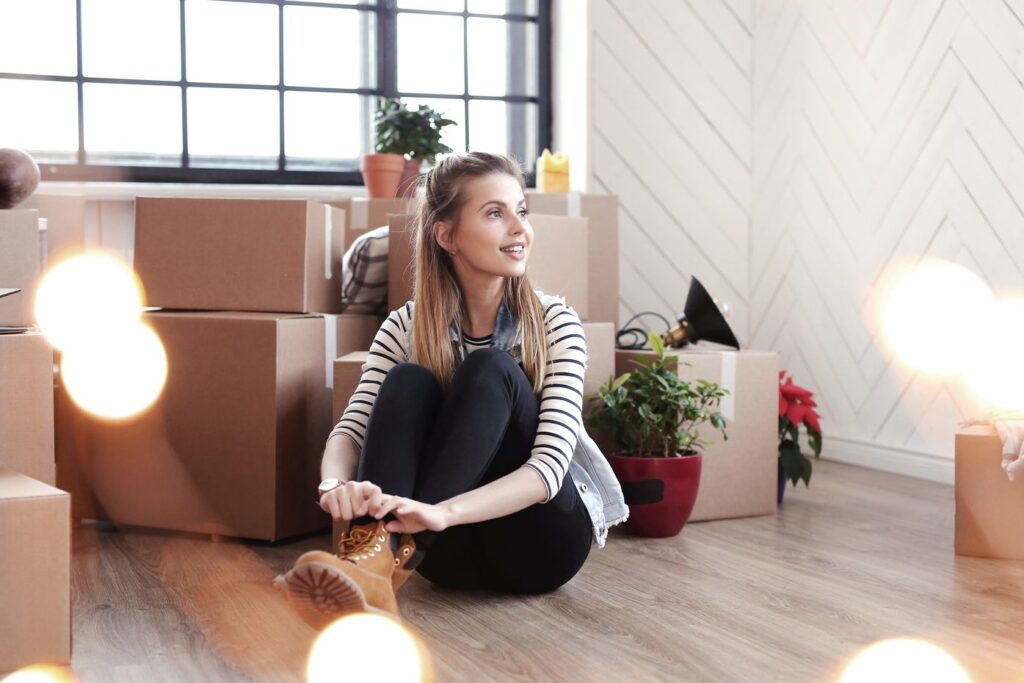 Girl sitting on the floor surrounded by packages and plants, waiting for Orange County movers